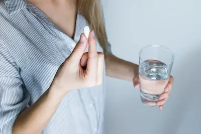 Patient taking pain killers with a glass of water